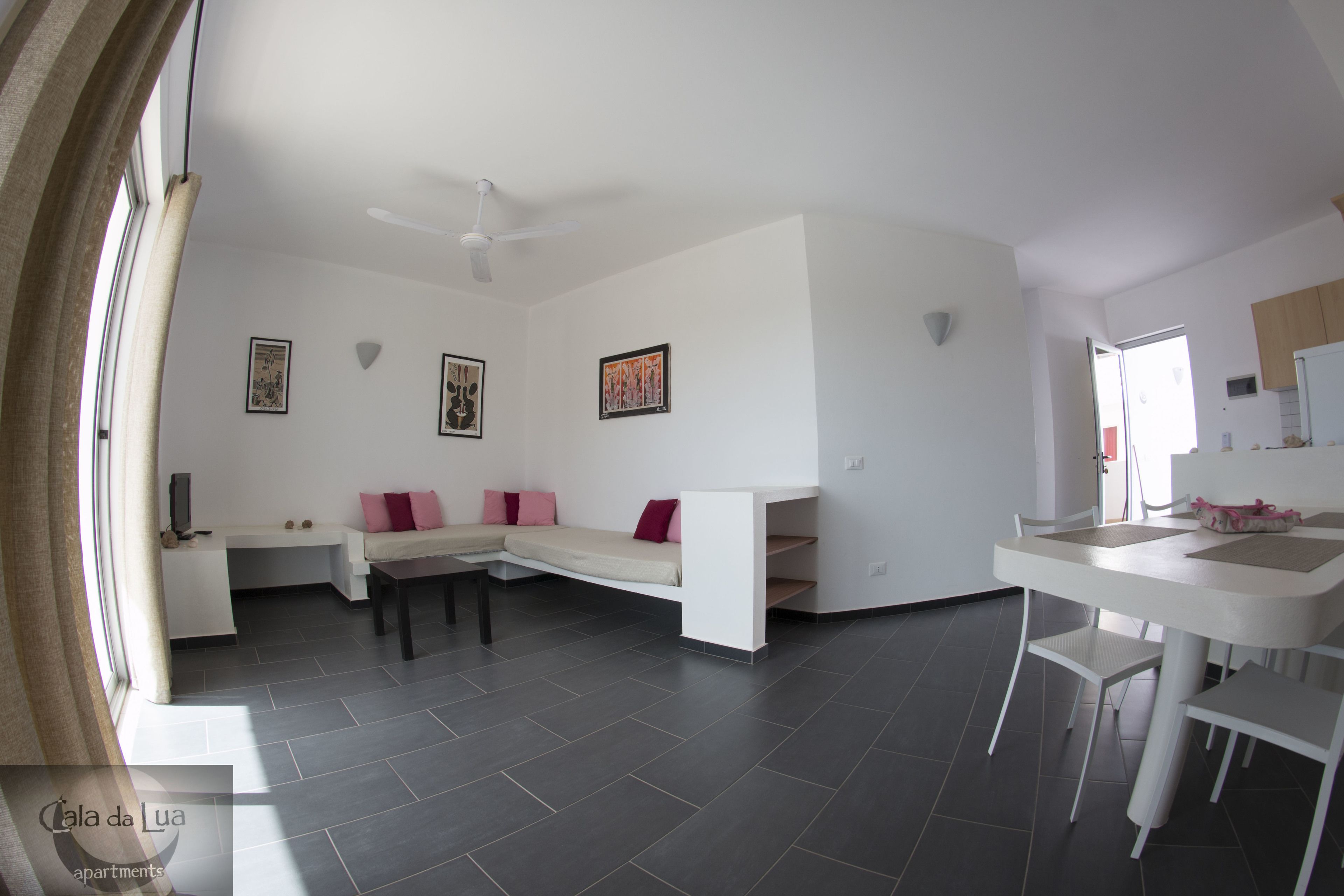 A modern living room with a sofa, a dining table, and a kitchen area.