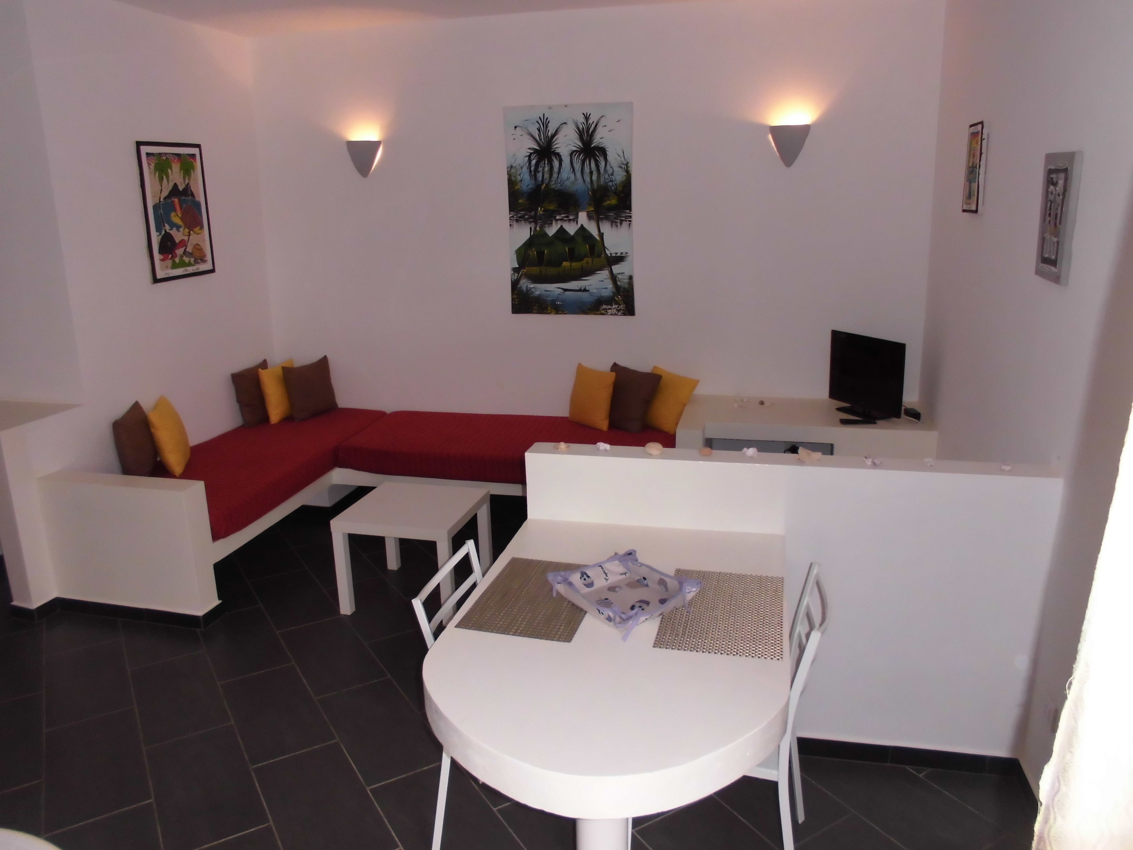 Una sala de estar moderna con un sofá seccional rojo, una mesa de comedor blanca y un televisor de pantalla plana.