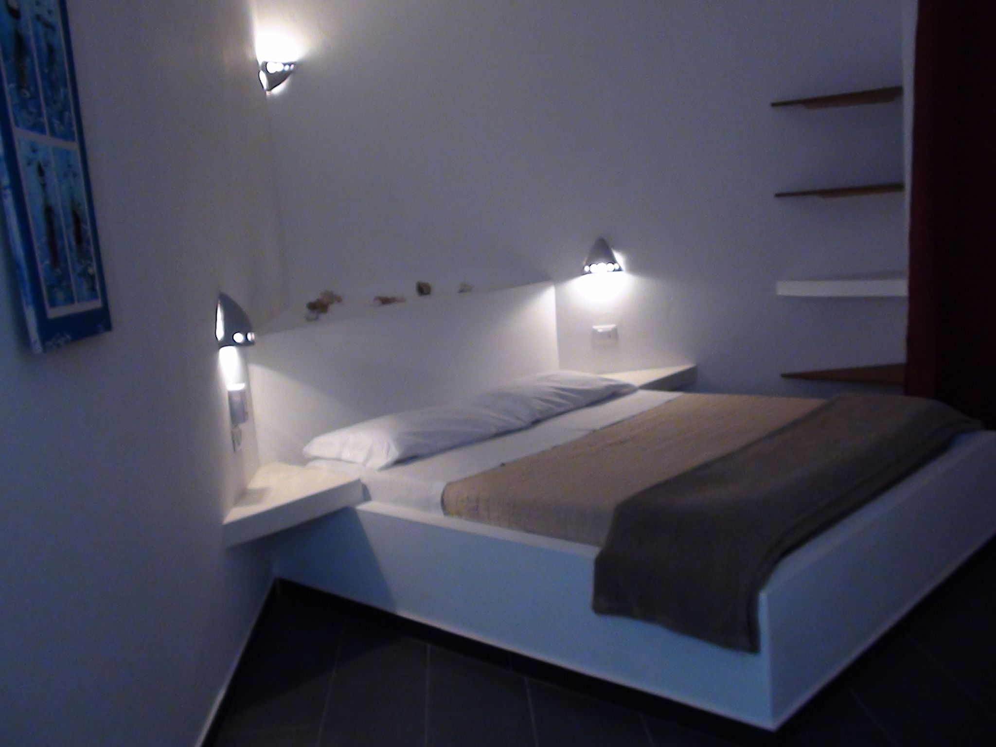 Ein modernes Schlafzimmer mit einem Bett, Nachttischen und Wandleuchten.