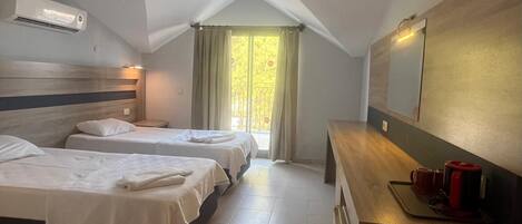 Una habitación de hotel con dos camas, un escritorio de madera, un espejo y una ventana con cortinas.