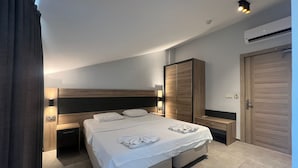 Een moderne hotelkamer met een groot bed, nachtkastjes, een kledingkast en een airconditioner.