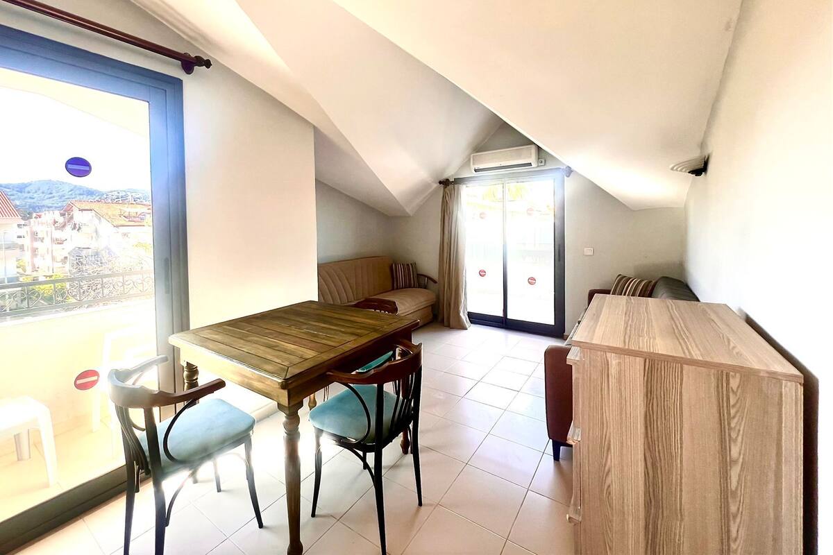 Un espace de vie compact comprenant une table à manger, des chaises, un canapé et une petite kitchenette.