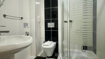 Un baño con un lavamanos blanco, un inodoro y una ducha con mampara de vidrio.