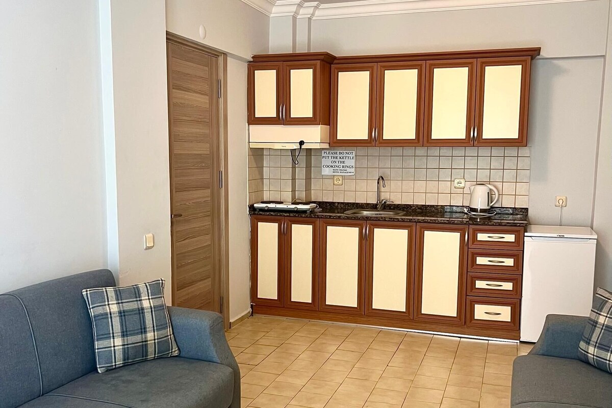 A compact living space with a kitchenette, two sofas, and a small dining table.
