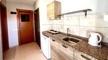 A compact kitchen with a built-in dishwasher, a sink, and a coffee maker.