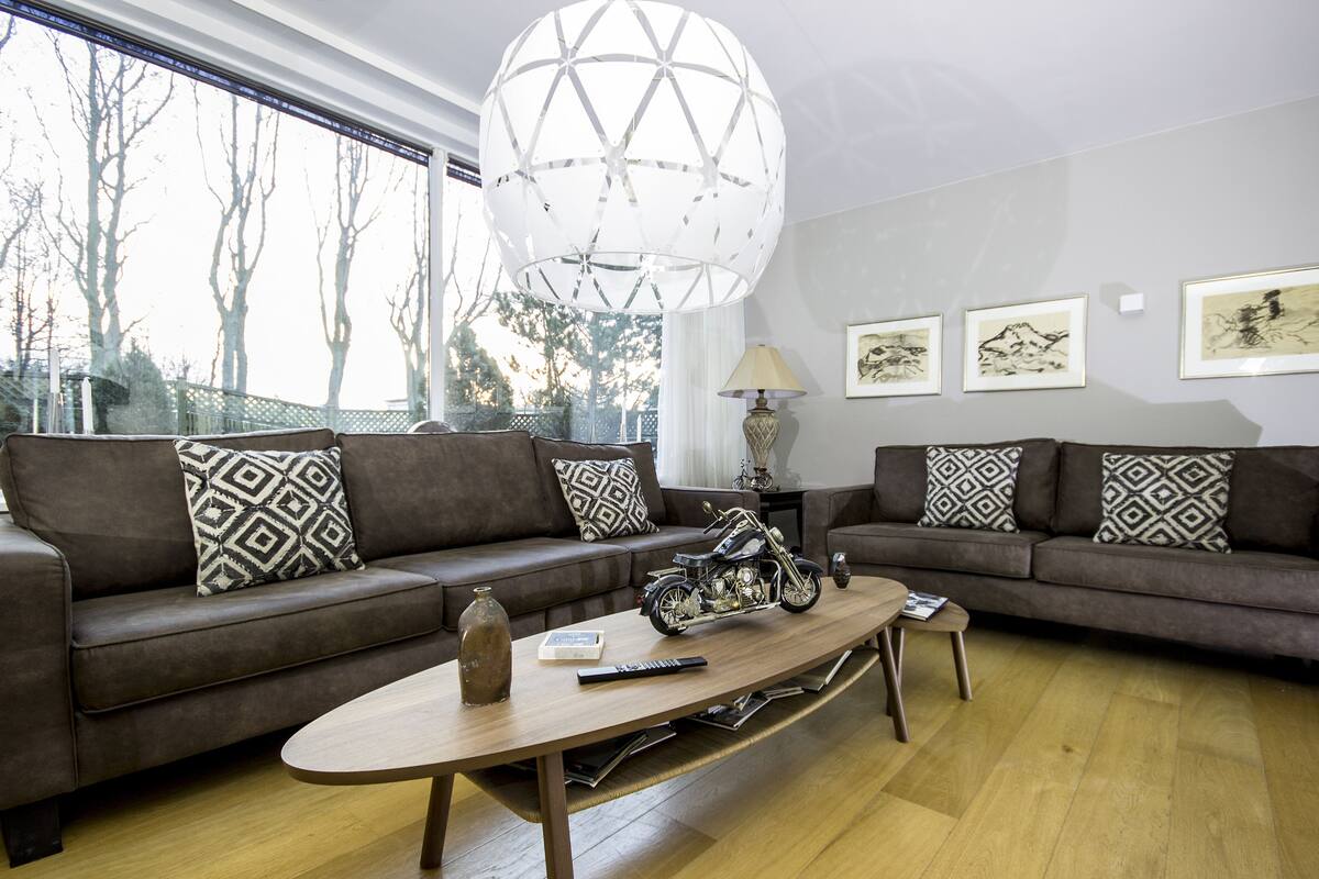 Uma sala de estar moderna com dois sofás, uma mesa de centro e uma réplica de moto.