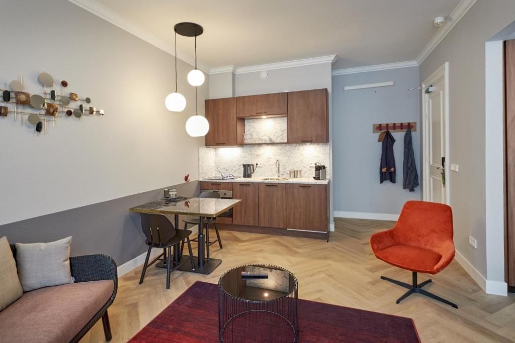 Un salon moderne comprenant un canapé, une table à manger et un coin cuisine avec des meubles en bois et un dosseret en marbre.