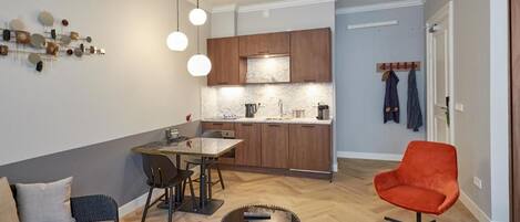 Un salon moderne comprenant un canapé, une table à manger et un coin cuisine avec des meubles en bois et un dosseret en marbre.