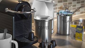 Una macchina da caffè, un bollitore e una tazza di caffè su un piano di lavoro in cucina.