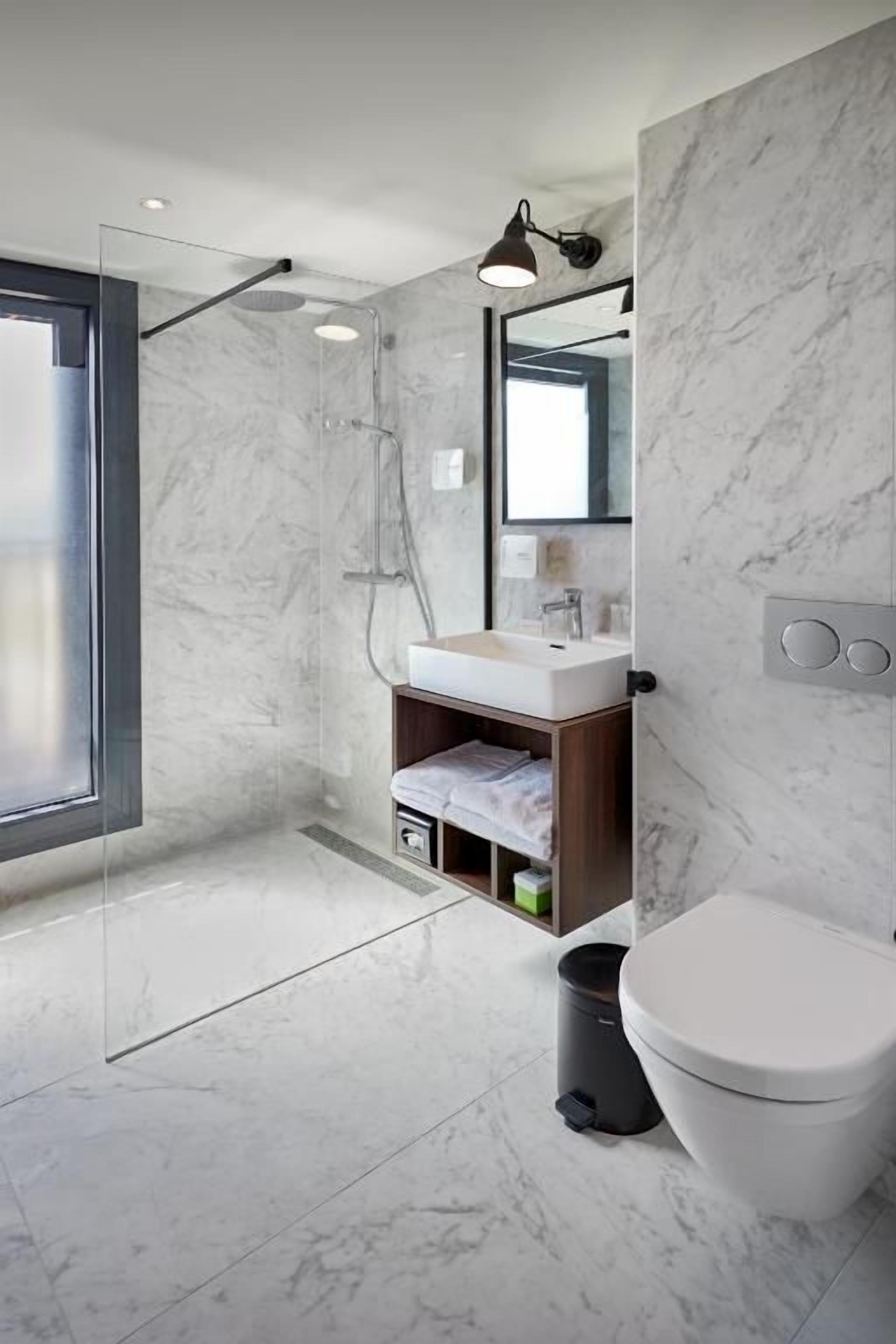 A modern bathroom with a glass shower enclosure, a white sink, and a toilet.