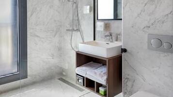 A modern bathroom with a glass shower enclosure, a white sink, and a toilet.