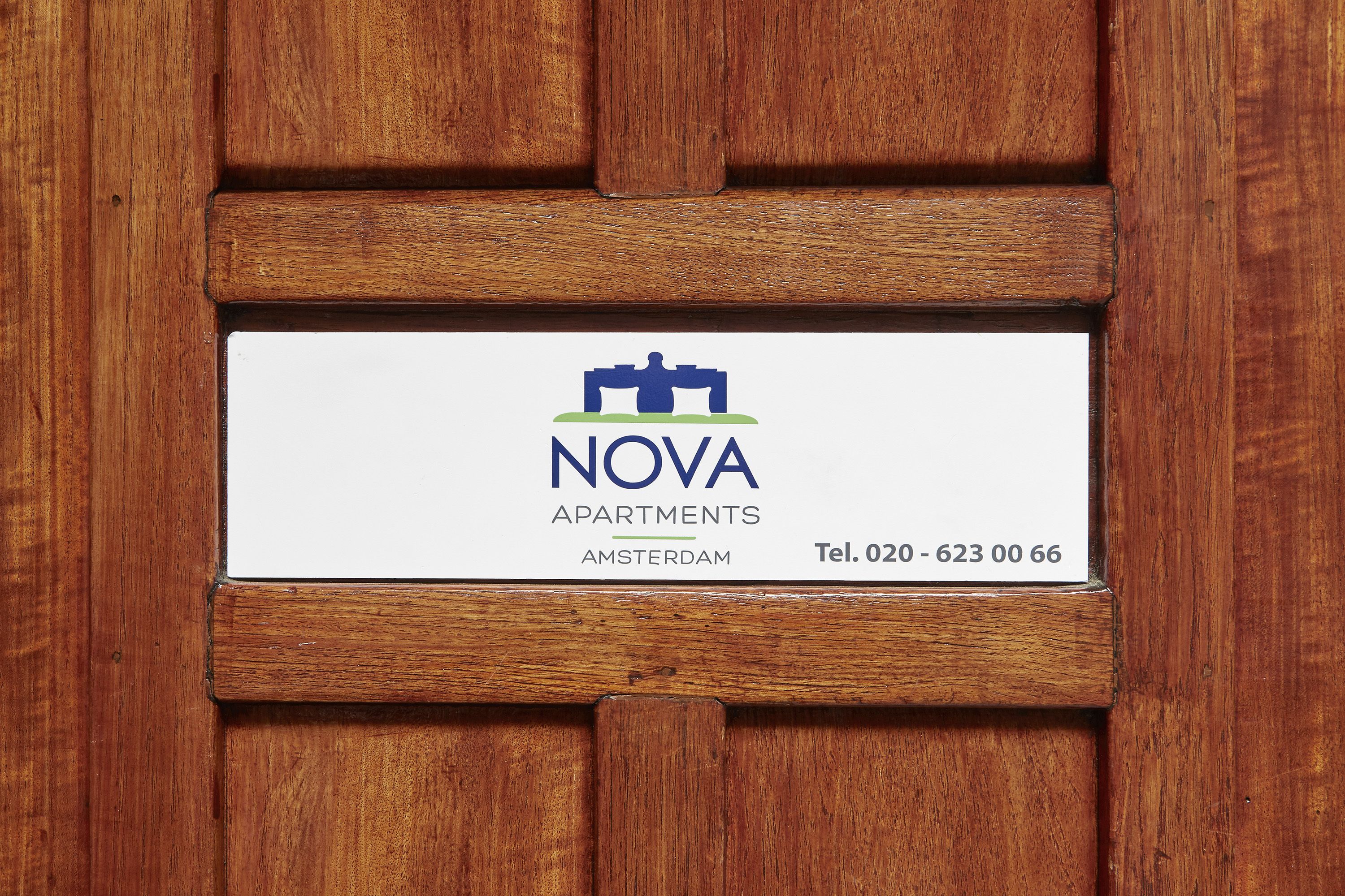 A sign for NOVA APARTMENTS in Amsterdam with a contact number.