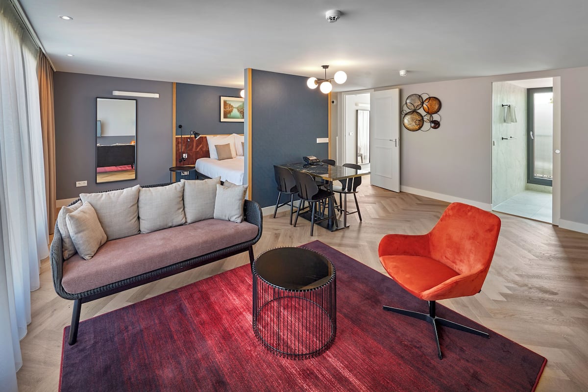 Un salon moderne avec un canapé, une table basse ronde et un fauteuil orange. On y trouve également un coin repas avec une table et des chaises.