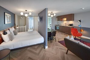 A modern hotel room with a bed, a desk, a chair, and a kitchenette. - Nova Apartments (Amsterdam)
