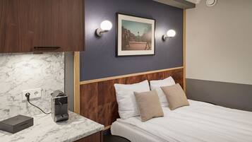 Una habitación de hotel con una cama, una encimera de mármol, un pequeño calentador y un cuadro en la pared.