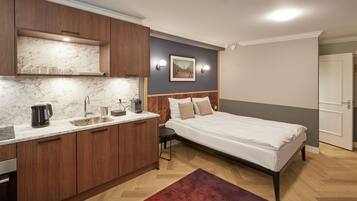 A modern bedroom with a bed, bedside table, and a nightstand. There is a built-in wardrobe and a small seating area with a chair.