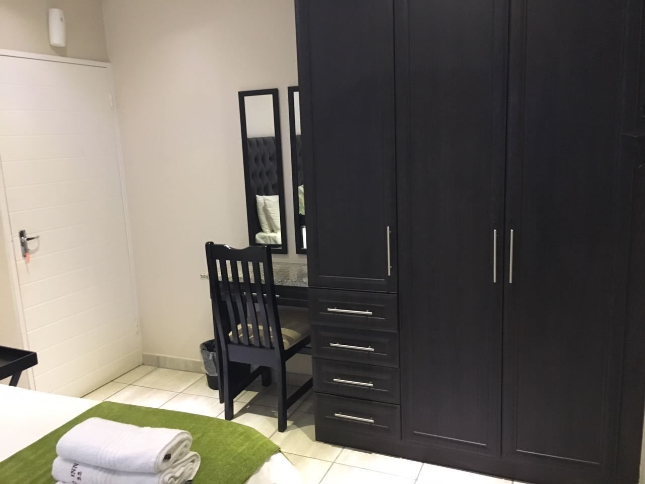 Un dormitorio con cama, escritorio, silla, armario y un cubo de basura.