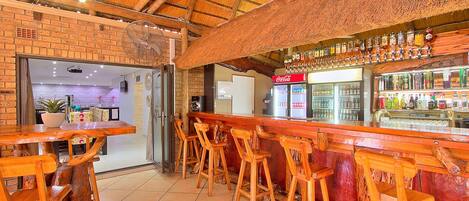 A bar area with wooden stools and a brick wall.