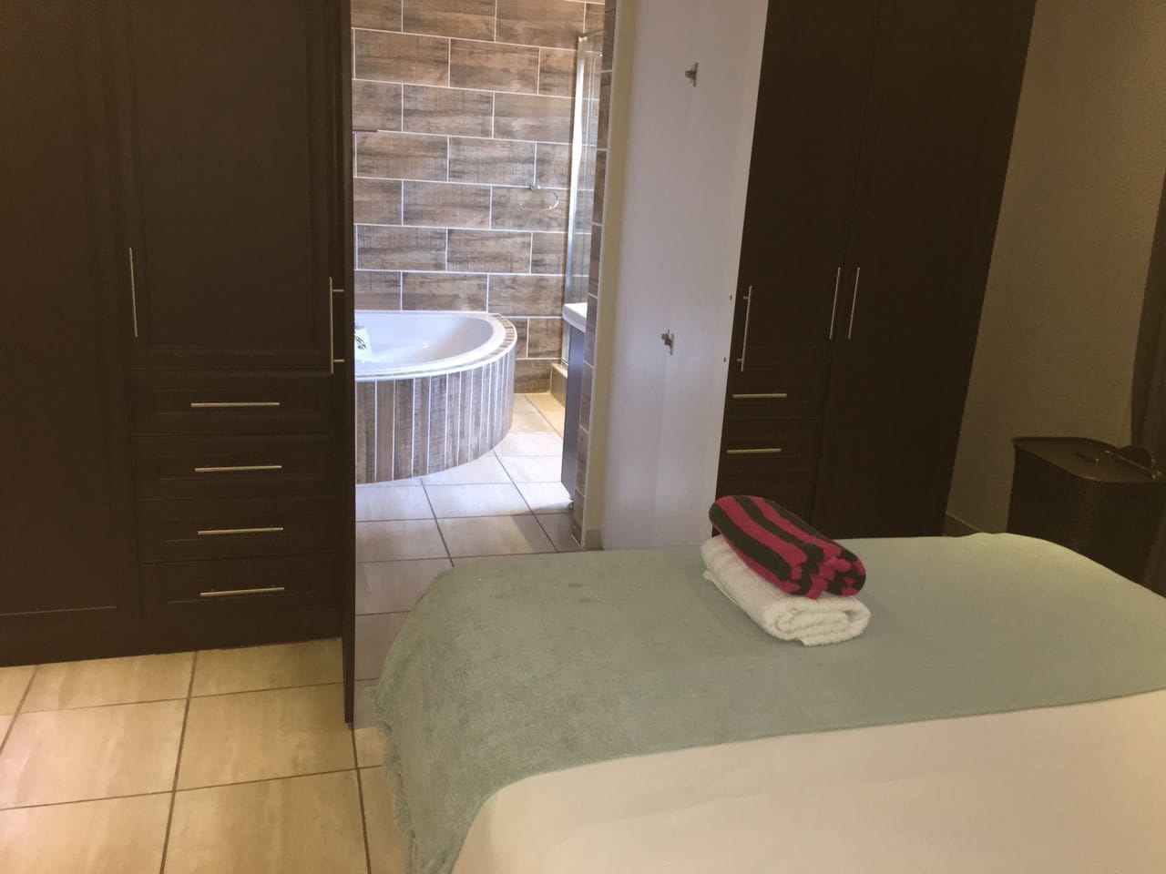 Une chambre d’hôtel avec un lit, une salle de bain avec une baignoire et une armoire.