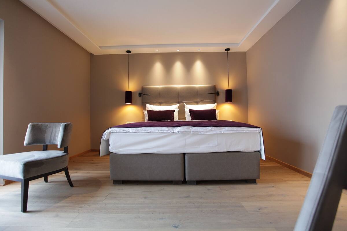 A modern bedroom with a large bed, two bedside tables, and a chair.