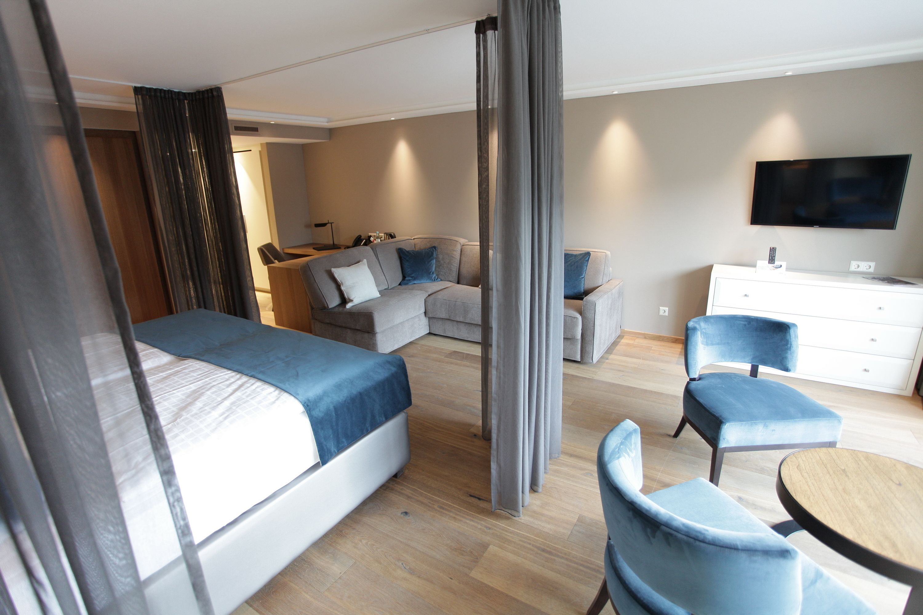 Una habitación de hotel con una cama, un sofá, un escritorio, una silla y un televisor.