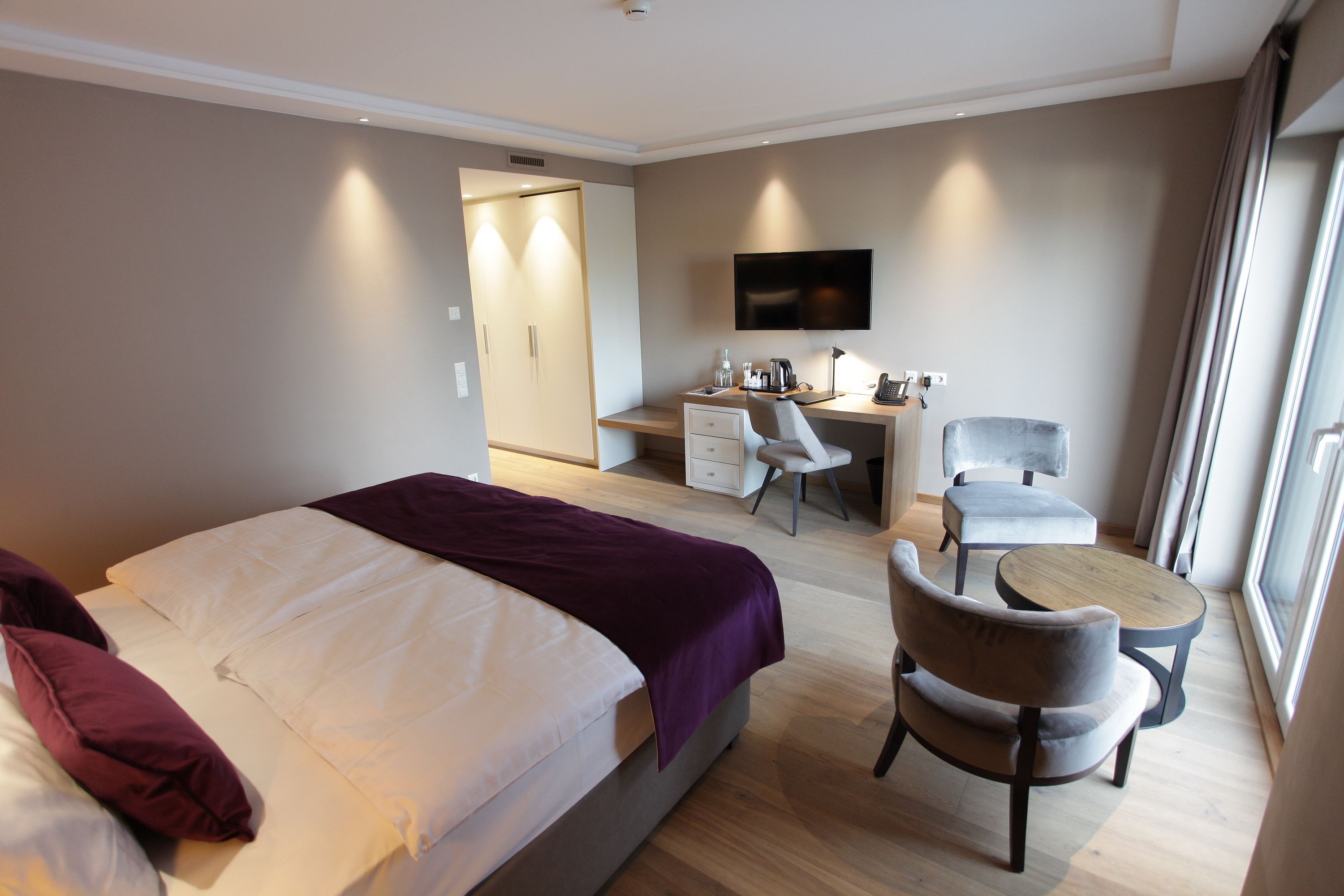 Una habitación de hotel con una cama, un escritorio con una silla, un televisor y una ventana.