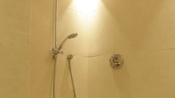Eine Eckdusche mit Handbrause und am Wand montiertem Wasserhahn.