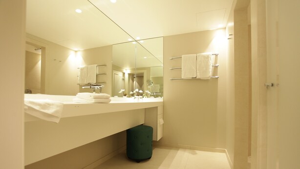 A modern bathroom with a large mirror, a vanity with a sink, and a toilet. - Hotel Aurelia (Aldingen)