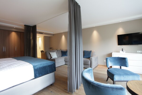 A modern hotel room with a large bed, a sofa, a TV, and a desk. - Hotel Aurelia (Aldingen)