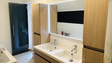 A modern bathroom with two sinks, a large mirror, and wooden cabinetry.