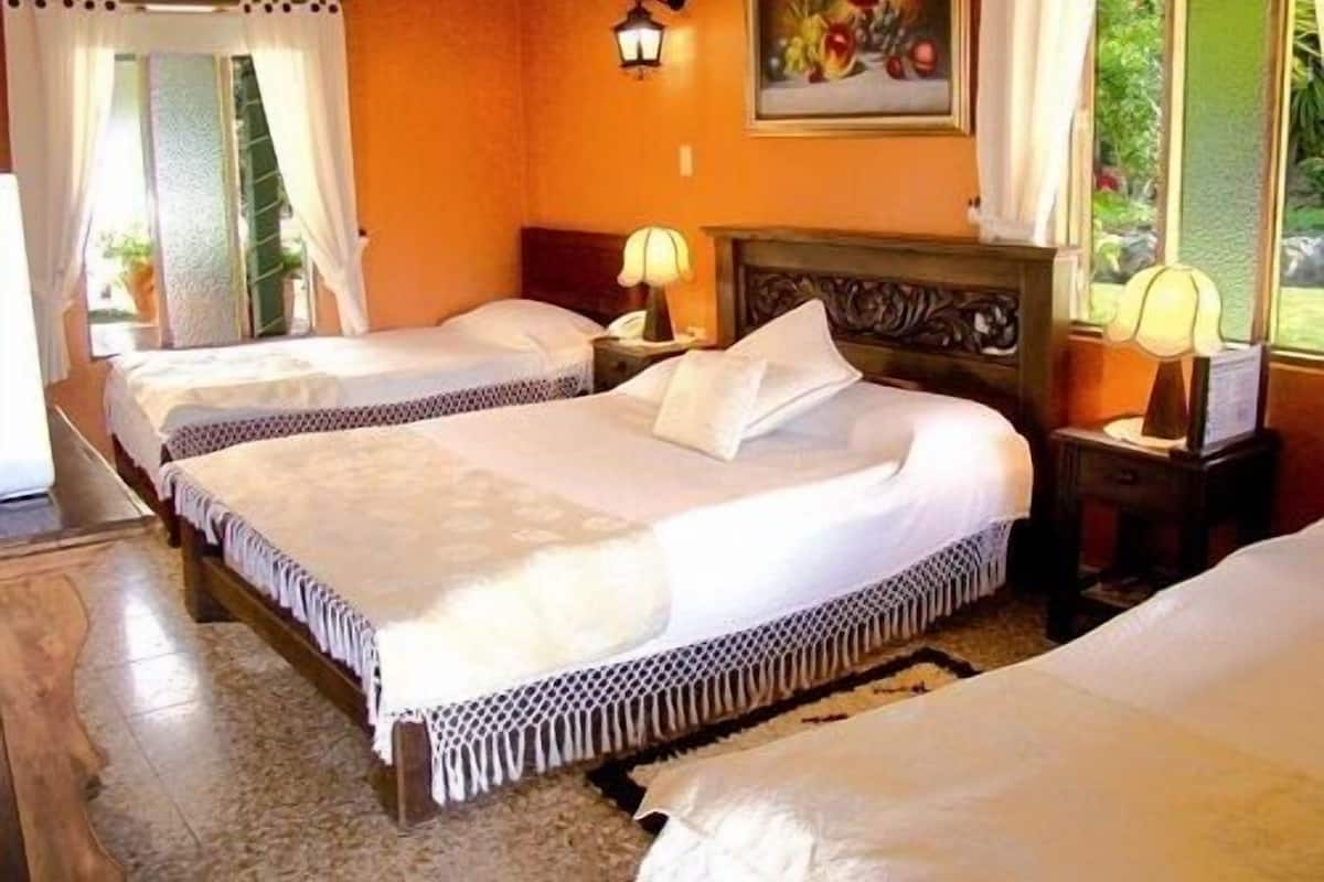 A hotel room with two beds, a painting on the wall, and a window with curtains.