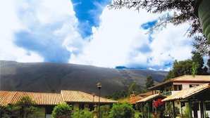 A courtyard with a fountain, surrounded by buildings with tiled roofs, set against a mountainous backdrop. - Hotel Iguaque Campestre Spa & Ecolodge (Villa de Leyva)