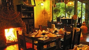A restaurant with a central fire feature, wooden tables, and chairs. - Hotel Iguaque Campestre Spa & Ecolodge (Villa de Leyva)