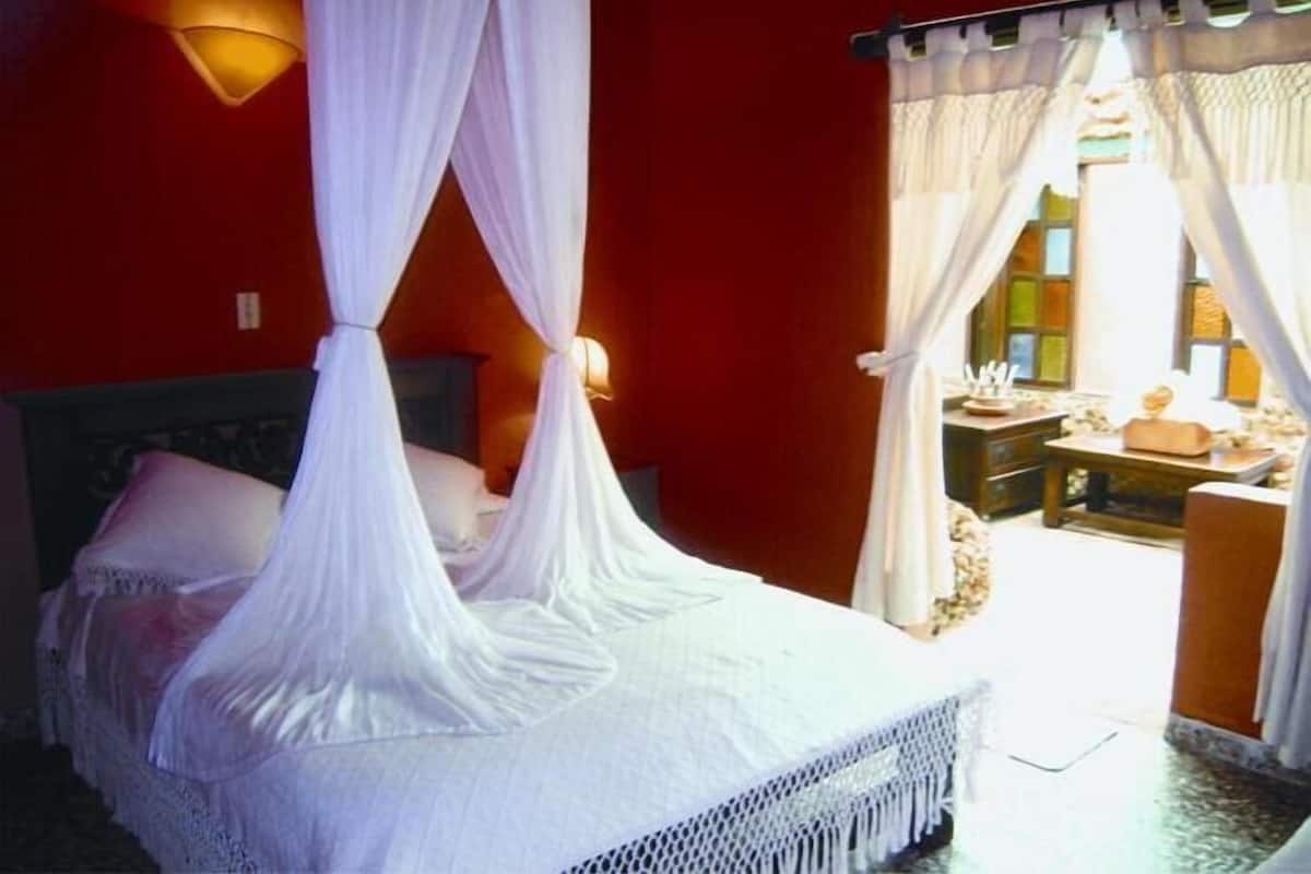 A bed with a canopy, a bedside table, and a view of an outdoor area with a table and chairs.
