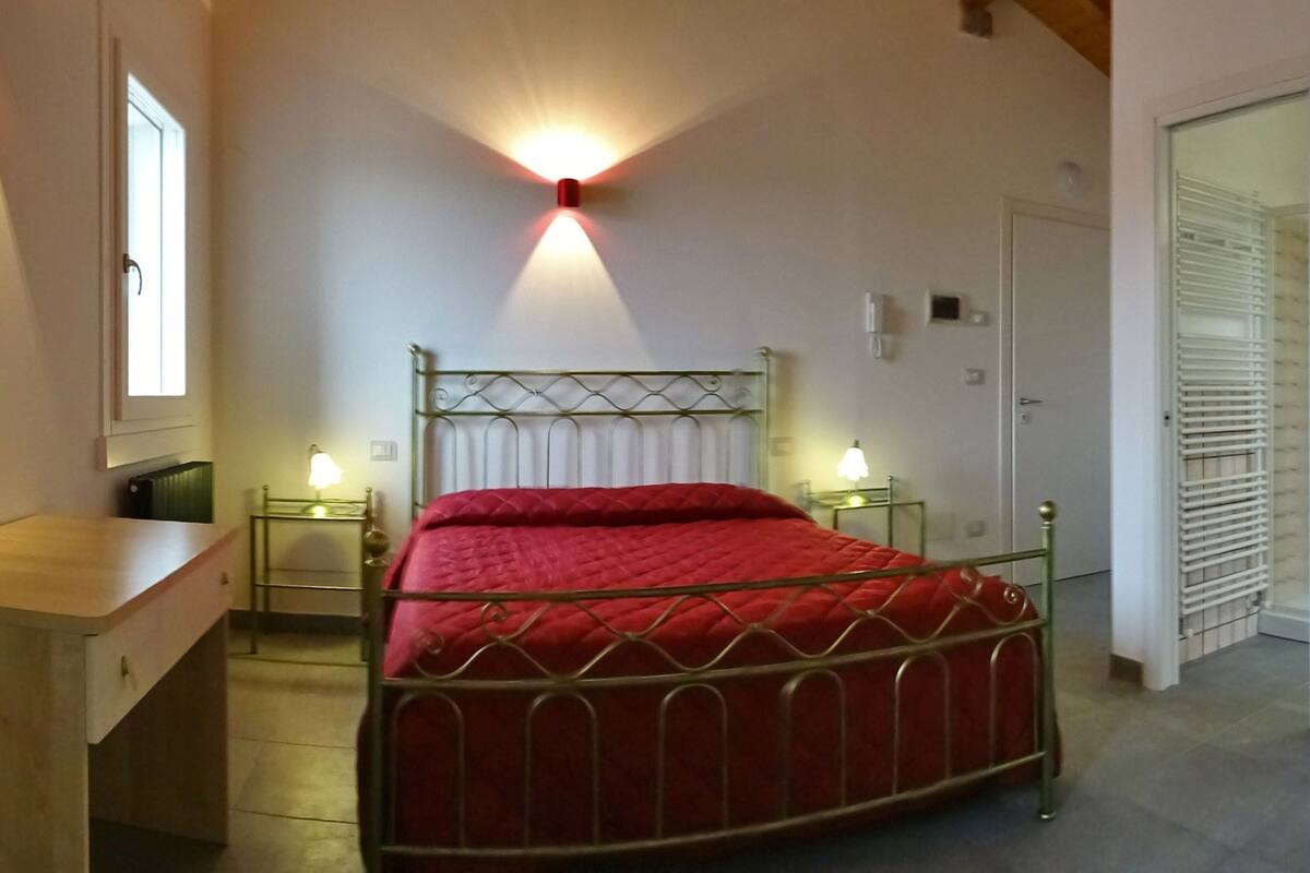 Quarto com cama, mesas de cabeceira, escrivaninha e guarda-roupa.