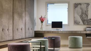 Un salon moderne avec un grand canapé, des poufs, un téléviseur à écran plat et des œuvres d’art accrochées au mur.