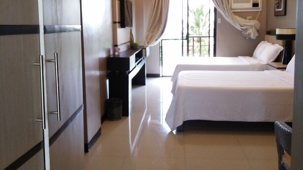 A hotel room with a bed, a desk, a TV, and a sliding glass door to the outside. - Belize Tagaytay (Tagaytay)