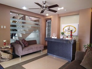 A modern reception area with a sofa, a reception desk, a ceiling fan, and a staircase. - Belize Tagaytay (Tagaytay)
