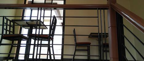 A staircase with a wooden handrail and metal railings, leading to a room with a table and chairs.