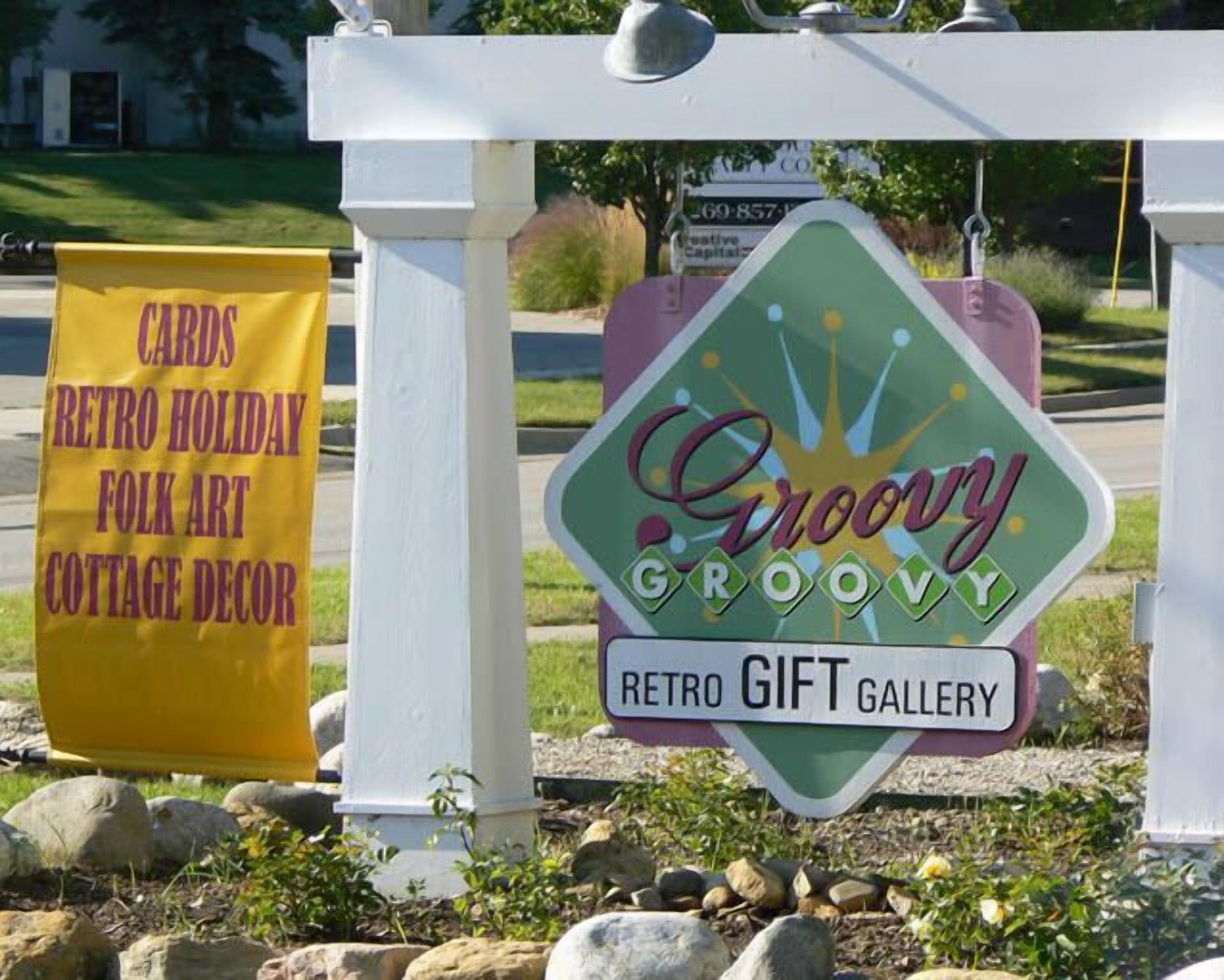 Une enseigne pour la « Galerie de cadeaux rétro Groovy Groove », avec une banderole indiquant : « Cartes, décorations de Noël rétro, art populaire, décoration de style champêtre ».