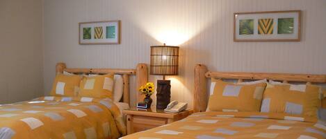 Une chambre d’hôtel avec deux lits, une table de chevet avec une lampe, un téléphone et une table avec une bouteille et des verres.