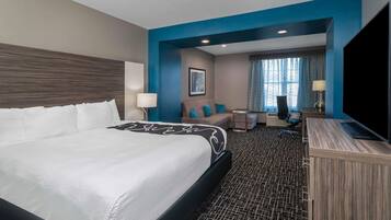 A hotel room with a large bed, a desk, a chair, and a sofa.