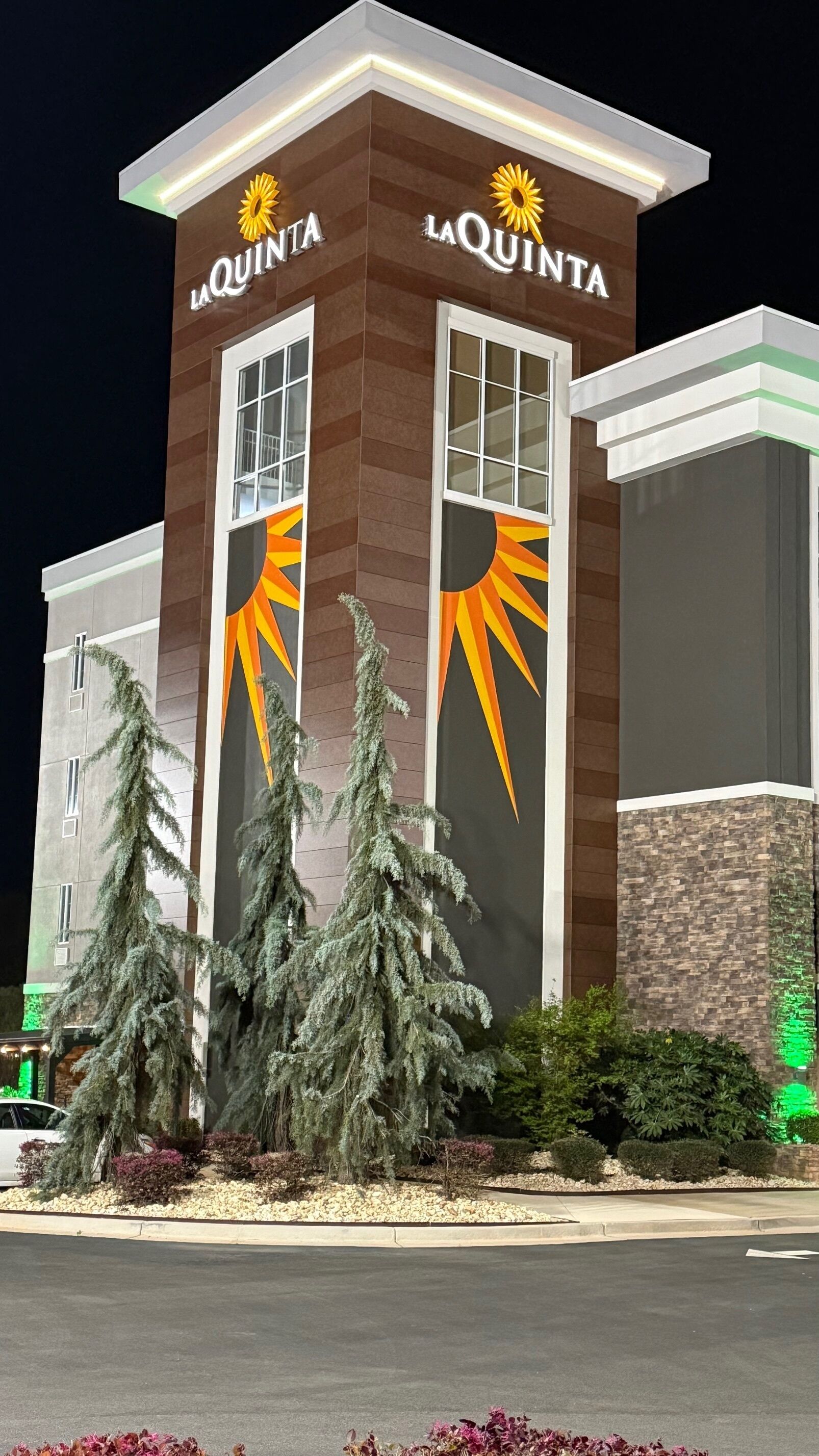 A La Quinta hotel building with a modern design, featuring a prominent logo and a large sun graphic on the facade.