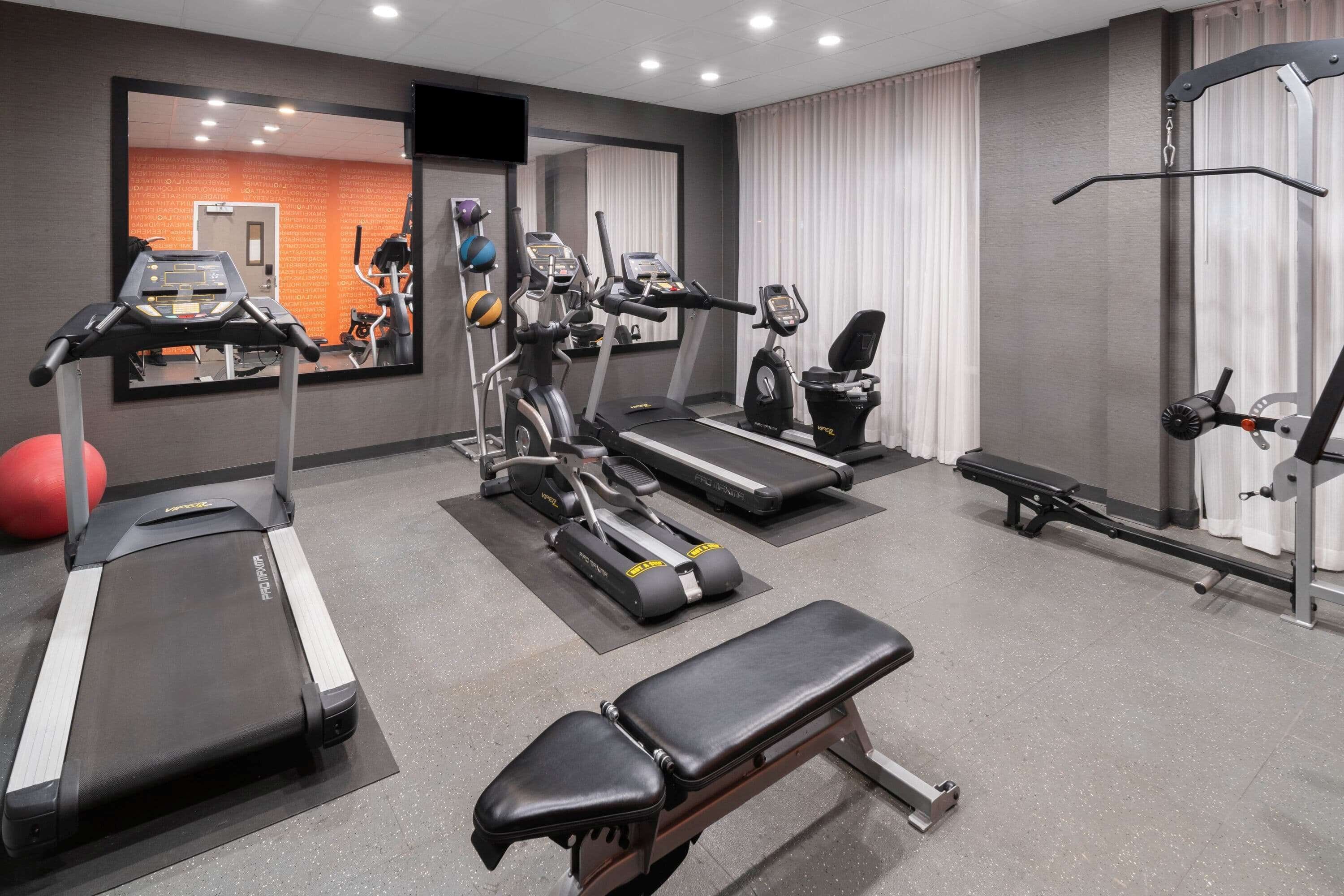 A gym with treadmills, elliptical machines, a bench, and a rowing machine.