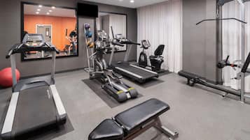 A gym with treadmills, elliptical machines, a bench, and a rowing machine.