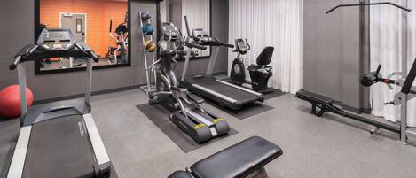 A gym with treadmills, elliptical machines, a bench, and a rowing machine.
