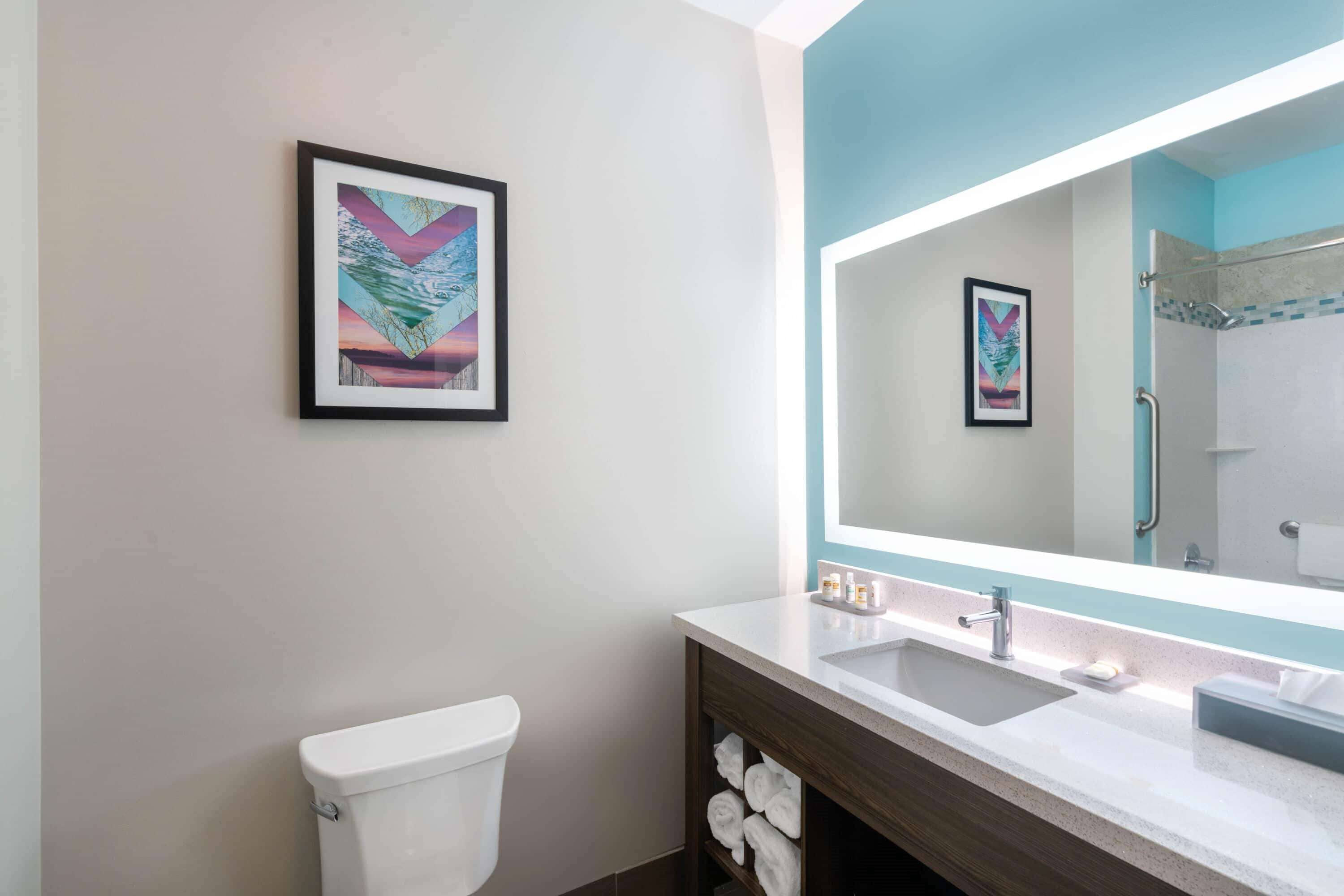 Une salle de bain moderne équipée d’un WC, d’un lavabo, d’un miroir et d’un porte-serviettes.