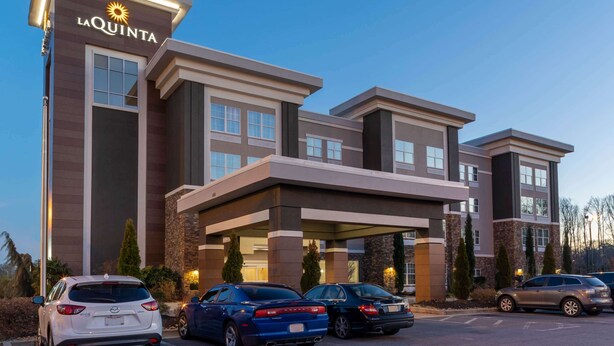 A hotel with a modern design, featuring a prominent entrance and multiple parking spaces. - La Quinta Inn & Suites by Wyndham Forsyth (Forsyth)