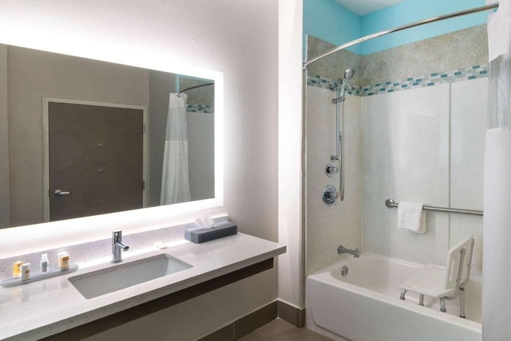Uma casa de banho moderna com um espelho grande, um lavatório, um chuveiro e uma banheira.