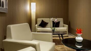 Una sala de estar moderna con un sofá, un sillón y una mesa de centro. Hay dos jarrones con flores sobre la mesa de centro.